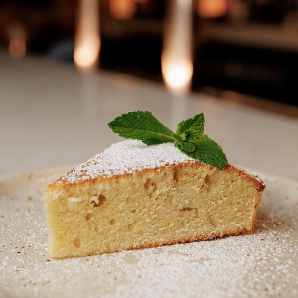 A slice of cake dusted with powdered sugar and garnished with mint leaves on a plate.